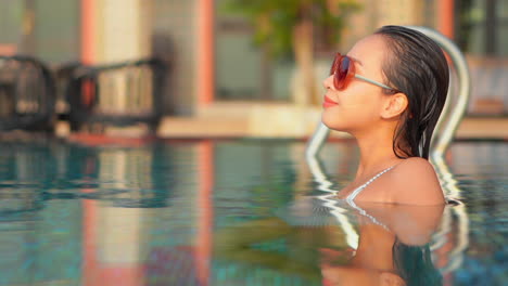 Junge-Frau,-Die-Im-Hotelschwimmbad-Chillt,-Gesichtsnahaufnahme-Auf-Unscharfem-Hintergrund-Bei-Sonnenuntergang-In-Miami-Florida