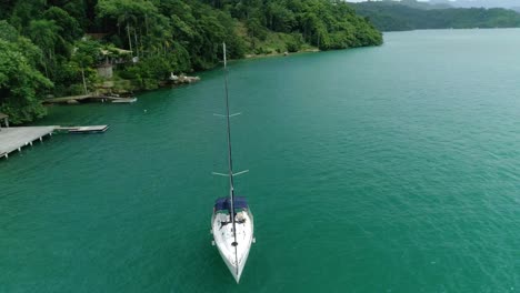 Aerial-drone-orbiting-shot-of-moored-sail-boat-near-pier-of-a-wonderful-tropical-island