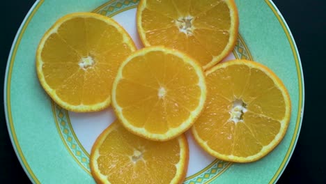 View-from-above-of-orange-slices-on-a-plate-while-the-camera-rotates