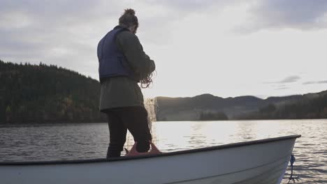 Hombre-De-Pie-Y-Arregla-La-Red-De-Pesca-En-El-Barco-Durante-La-Puesta-De-Sol-En-Noruega