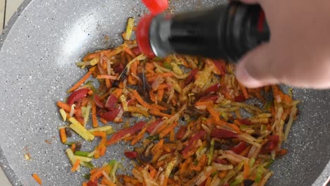 Man's-hand-adding-soy-sauce-to-frying-vegetables-in-a-wok
