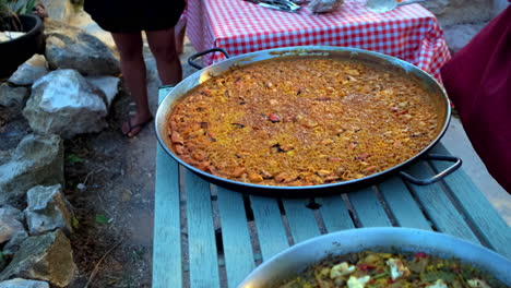 Slow-motion-shot-of-a-large-pan-filled-with-Paella,-a-Spanish-rice-dish-on-a-small-market