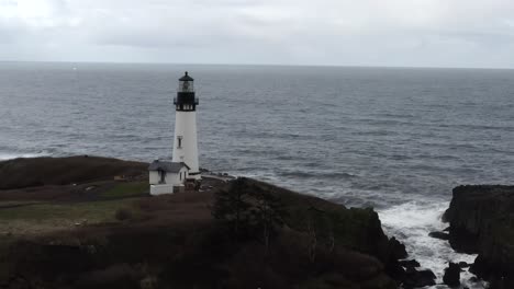 Yaquina-Head-Lighthouse,-Pacific-Ocean-in-Newport-Oregon,-aerial-view-pass-by-over-waves