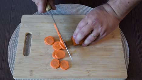 Man's-hand-cutting-a-carrot.Top-view