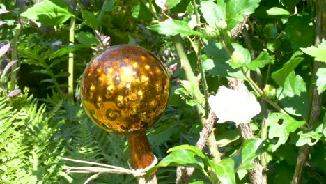 Golden-shiny-rose-ball-in-a-garden-between-flowers