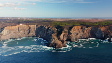 Aerial-dolly-forward-of-beautiful-algarve-coastline-with-cliff-rocks-and-splashing-ocean-water-in-bay