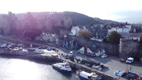 Idyllic-Conwy-castle-and-harbour-fishing-town-boats-on-coastal-waterfront-aerial