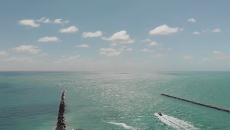 Luftaufnahme-Des-Ozeans-In-Miami-Beach,-Ein-Boot-Segelt-Zwischen-Wellenbrechern-In-Richtung-Ozean,-Zeitlupe