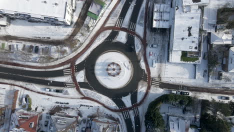 Top-down-aerial-of-traffic-using-roundabout-in-winter---drone-lifting-up