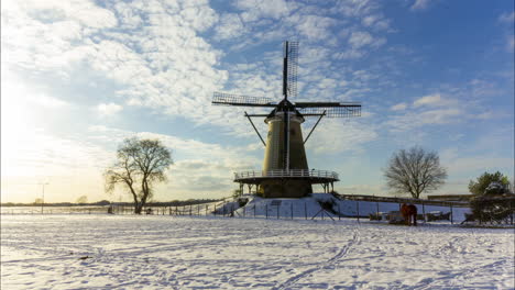 Zeitraffer-Von-Wolken,-Die-über-Eine-Traditionelle-Windmühle-In-Einer-Wunderschönen-Weißen-Winterlandschaft-Ziehen