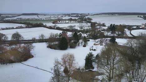 House-and-large-garden-Essex,-UK-fields-in-winter-with-snow-covering-Aerial-4k