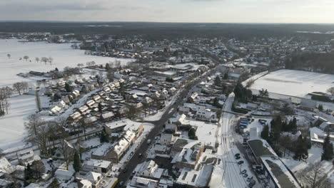 Aerial-of-busy-road-running-through-small-rural-town-in-winter