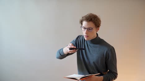 The-guy-with-glasses-takes-pictures-of-the-text-of-the-book-on-a-smartphone-for-digitization