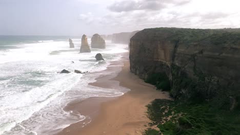 The-Twelve-Apostles,-a-major-tourist-highlight-of-Australia,-Great-Ocean-Road,-bird-flying-by,-pan-right,-slow-motion