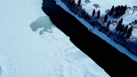 Aerial-birds-eye-view-flyover-dolly-roll-upwards-winter-snow-covered-partially-icy-North-Saskatchewan-River-by-Kinsmen-Park-empty-John-Walter-Museum-homestead-curve-flight-around-walter-dale-bridge1-3