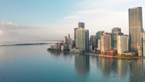 Luftaufnahme-Der-Innenstadt-Von-Miami-Südlich-Des-Miami-River-Brickell,-Der-Sich-Bei-Sonnenaufgang-Im-Wasser-Widerspiegelt