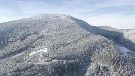 Tracking-Luftaufnahme-Eines-Alpinen-Berges,-Der-Im-Winter-Mit-Schneebedeckten-Bäumen-Bedeckt-Ist