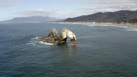 Twin-Rocks,-Rockaway-Beach,-aerial-low-orbit,-clear-afternoon
