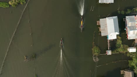 Top-down-aerial-of-long-boat-traveling-through-floating-village-at-Inle-Lake