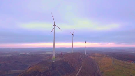 Dramatic-dense-mist-surrounding-wind-turbines-on-hill-with-colorful-sky-in-nature