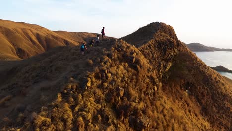 komodo-national-park-aerial-view-of-group-of-trekkers-hiking-the-Gili-Lawa-Darat-mountain-island-crest-rock-cliff-formation-for-the-sunrise-over-the-ocean