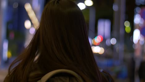 Slow-motion-rear-head-shot-with-bokeh-of-a-young,-Asian-female-tourist-walking-around-a-city-at-night