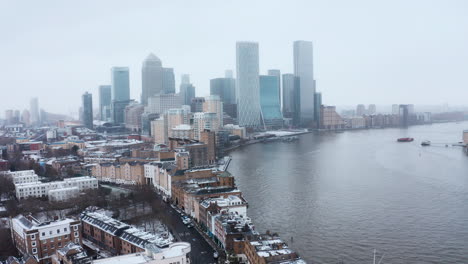 Circling-drone-shot-of-Canary-wharf-skyscrapers-in-the-snow-from-Limehouse