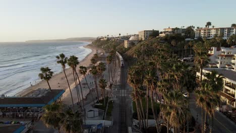 San-Clemente-train-along-Californian-Pacific-coast-at-sunset,-aerial-view