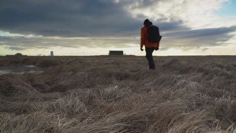 El-Hombre-Camina-En-El-Prado-En-Un-Día-Ventoso-Bajo-Un-Cielo-Nublado-En-Selfoss,-Islandia