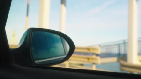 Rear-view-mirror-with-defocused-background,-driving-on-the-coast-side
