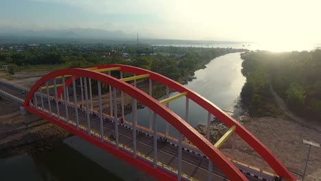 aerial-footage-of-big-highway-bridge-over-a-river-with-motorcycle-parking-and-driving-fast-during-sunset,-Samota-Bridge,-Sumbawa-indonesia