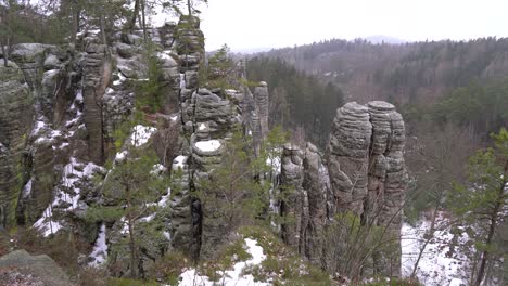 sandstone-rock-formation-with-snow-and-landscape-in-Prachov-Rocks,-Bohemian-Paradise,-tilt-up