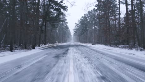Scenic-Road-Amidst-A-Snowy-Forest-On-A-Winter-Day---moving-shot
