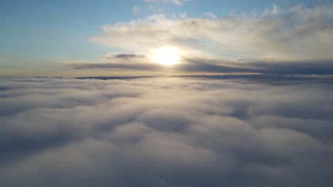 Zooming-out-drone-footage-above-the-clouds-at-sunset-time