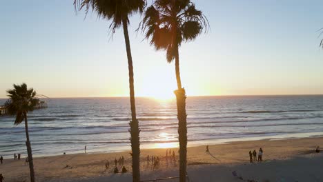Menschen,-Die-Während-Des-Sonnenuntergangs-Am-Sandufer-Des-San-Clemente-Beach-In-Der-Nähe-Des-Holzpiers-In-Kalifornien,-Usa,-Spazieren-Gehen