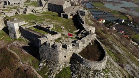 Beautiful-castle-with-stone-walls-built-on-top-of-hill-surrounded-by-fields-and-river-in-Shkoder,-Albania