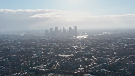 high-dolly-forward-drone-shot-towards-Canary-wharf-London-skyscrapers-day-after-snow