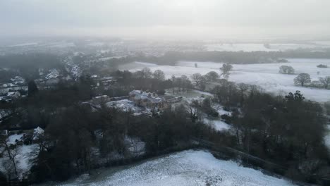 Schneebedeckte-Englische-Landschaft-Großes-Haus-Im-Vordergrund-Luftschwenk-4k