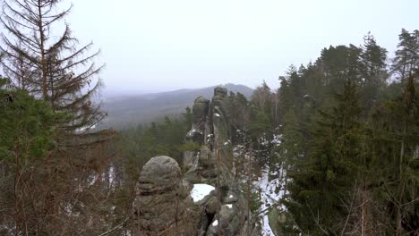 outlook-on-a-sandstone-rock-formation-in-Prachov-Rocks,-Bohemian-Paradise,-in-winter-with-flying-snowflakes,-truck-right