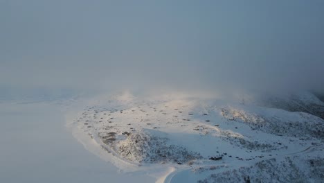 Atmosphärische-Drohnenaufnahmen-Von-Gefrorenen-Bergseen-Und-Schneebedeckten-Berghütten-Am-Ufer