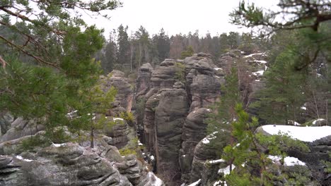 outlook-on-a-sandstone-rock-formation-through-branches-in-Prachov-Rocks,-Bohemian-Paradise,-in-winter,-tilt-up