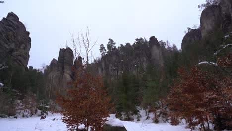 in-the-middle-of-a-sandstone-rock-town-in-Prachov-rocks,-Bohemian-Paradise-in-winter-with-flying-snowflakes,-pan-left