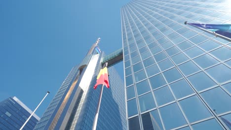 Belgian-flag-waving-slightly-in-front-of-glass-business-building-facade-in-Brussels,-Belgium
