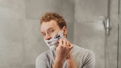 Handsome-young-guy-shaves-his-beard-with-a-razor