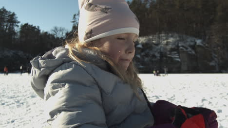 Young-girl-quenching-her-thirst-after-playing-in-the-snow-in-Lhotka-Frozen-lake-in-Kokorin,-Czech-Republic---close-up-slow-motion-static-shot