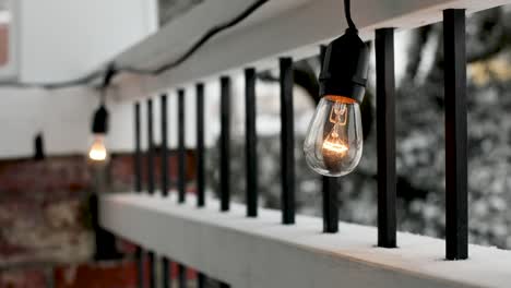 Close-up-shot-of-modern-lighting-bulb-lights-decorating-outdoors-at-terrace-during-snowy-day-in-winter