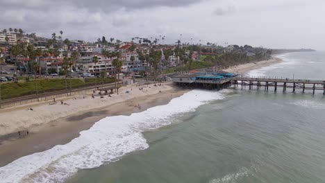 Aerial-view-of-beautiful-beach-with-pier-and-palm-trees-in-California