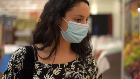 Young-attractive-Latina-woman-wearing-a-face-mask-shopping-at-a-grocery-store-during-a-pandemic