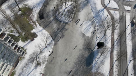 Luftaufnahme-Von-Menschen,-Die-Auf-Einem-Zugefrorenen-Teich-In-Den-Niederlanden-Eislaufen