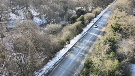 Straße-Durch-Den-Wald-Im-Winter-Großbritannien-Luftaufnahmen-Mit-Leichter-Schneedecke